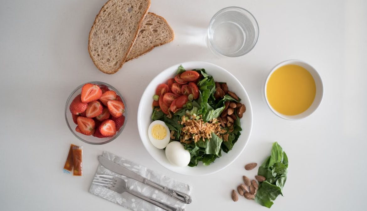 Top view of a nutritious breakfast with salad, eggs, bread, and juice, perfect for a healthy start.