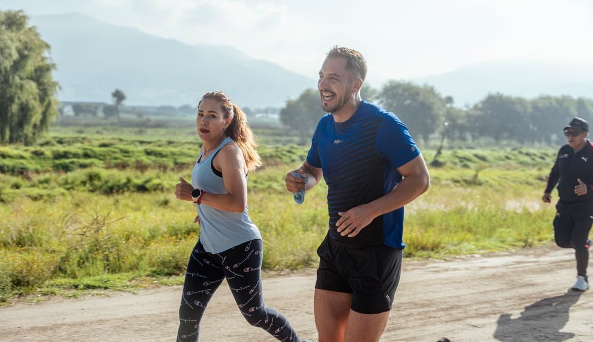 Two adults running on a rural dirt path, enjoying a sunny day outdoors.